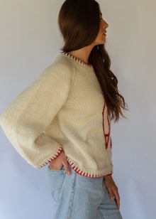 HOBO AND HATCH | Sol Sweater - Chilli - Hand-knitted cream wool sweater crafted from 100% New Zealand wool, featuring playful embroidered chilli motifs and contrasting red blanket-stitch detailing along the hem, neckline, and sleeves. Designed with a relaxed fit, round neckline, and open sleeves for effortless layering or standalone wear. Ethically handcrafted in Nepal alongside local artisans.