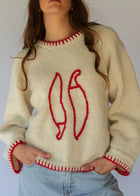 HOBO AND HATCH | Sol Sweater - Chilli - Hand-knitted cream wool sweater crafted from 100% New Zealand wool, featuring playful embroidered chilli motifs and contrasting red blanket-stitch detailing along the hem, neckline, and sleeves. Designed with a relaxed fit, round neckline, and open sleeves for effortless layering or standalone wear. Ethically handcrafted in Nepal alongside local artisans.