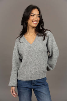 Humidity Lifestyle Nouveau V Neck Jumper in a soft wool blend, featuring a relaxed, oversized fit with a low V-neckline and subtle bell sleeves. Designed with ribbed cuffs and hem that sit just below the hips, this plush, lightweight jumper has a gentle, fluffy texture ideal for layering over denim or dresses.