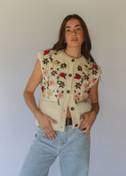 HOBO AND HATCH | Petal Vest - Hand-knitted cream wool vest crafted from 100% New Zealand wool, featuring delicate floral embroidery inspired by spring blooms, coconut button closure, and front patch pockets. Designed with a relaxed silhouette for effortless layering over winter knitwear or pairing with denim. Ethically handcrafted in Nepal alongside local artisans.